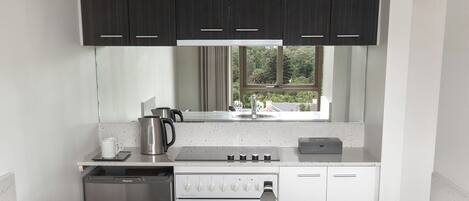 A modern kitchen with dark cabinets, a stainless steel sink, a stove, and a dishwasher.