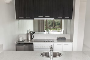 Enjoy cooking in this kitchen with sleek cabinetry, a stainless steel sink, and a compact stove.