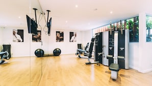 A modern gym with exercise equipment, large mirrors, and posters on the walls. - Haven Glebe (Glebe)