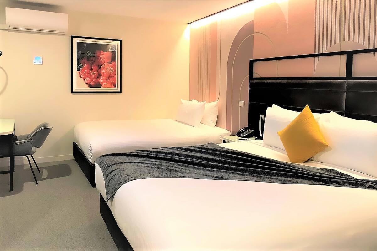 A hotel room with two beds, a desk, and a chair.