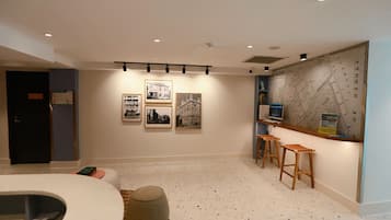 A modern hotel room with a large map on the wall, a seating area with stools, and a small round ottoman.