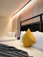 A hotel room with two beds, a modern headboard, and a wall-mounted phone.
