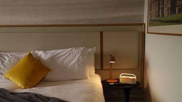Una habitación de hotel con una cama, una mesita de noche con una lámpara y un cuadro en la pared.