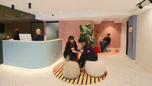 A modern reception area with a blue-tiled counter, round seating, and a large potted plant. - Haven Glebe (Glebe)