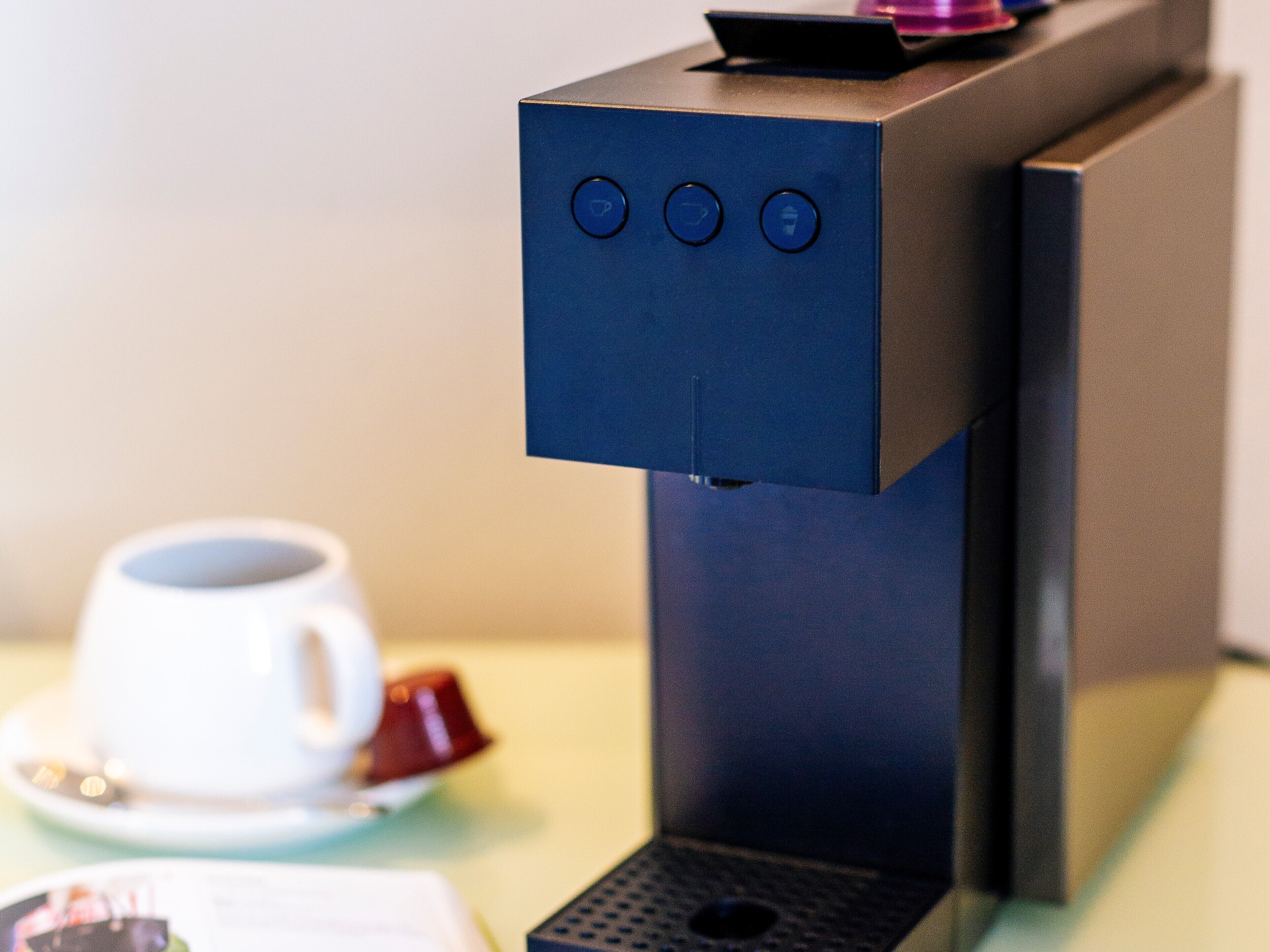 Une machine à café dotée d’un panneau de commande et d’une tasse posée sur une table.