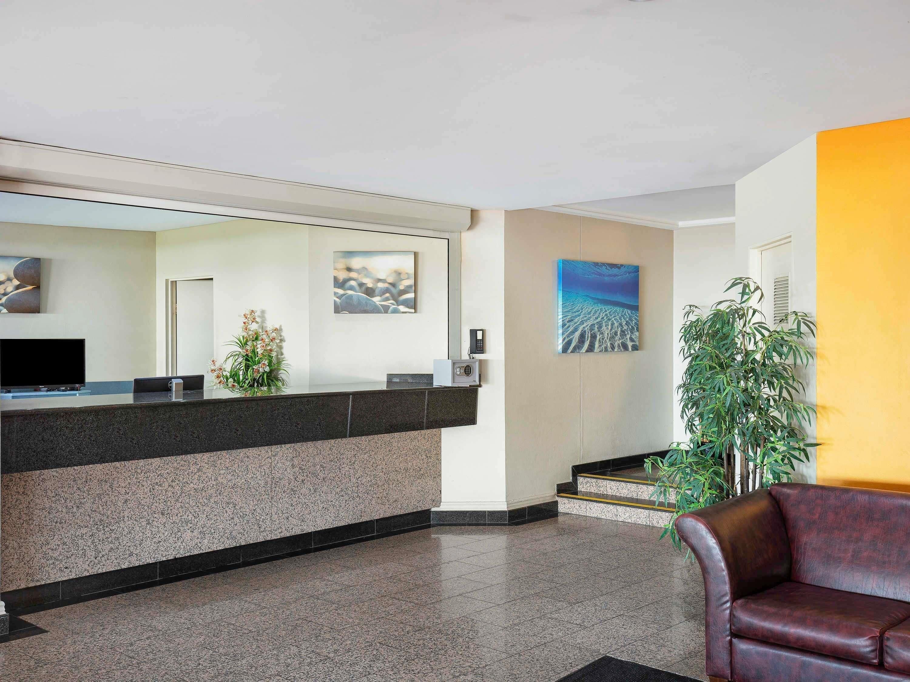 A reception area with a counter, a television, a plant, and artwork on the walls.