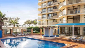 A hotel with a swimming pool, lounge chairs, and a covered seating area. - Breakfree Imperial Surf (Surfers Paradise)