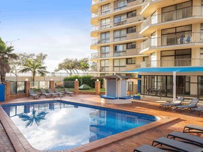 A hotel with a swimming pool, lounge chairs, and a covered seating area. - Breakfree Imperial Surf (Surfers Paradise)