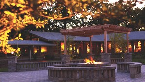 A fire pit area with a pergola structure, surrounded by stone benches and a brick pathway. - Lake Lawn Resort (Delavan)