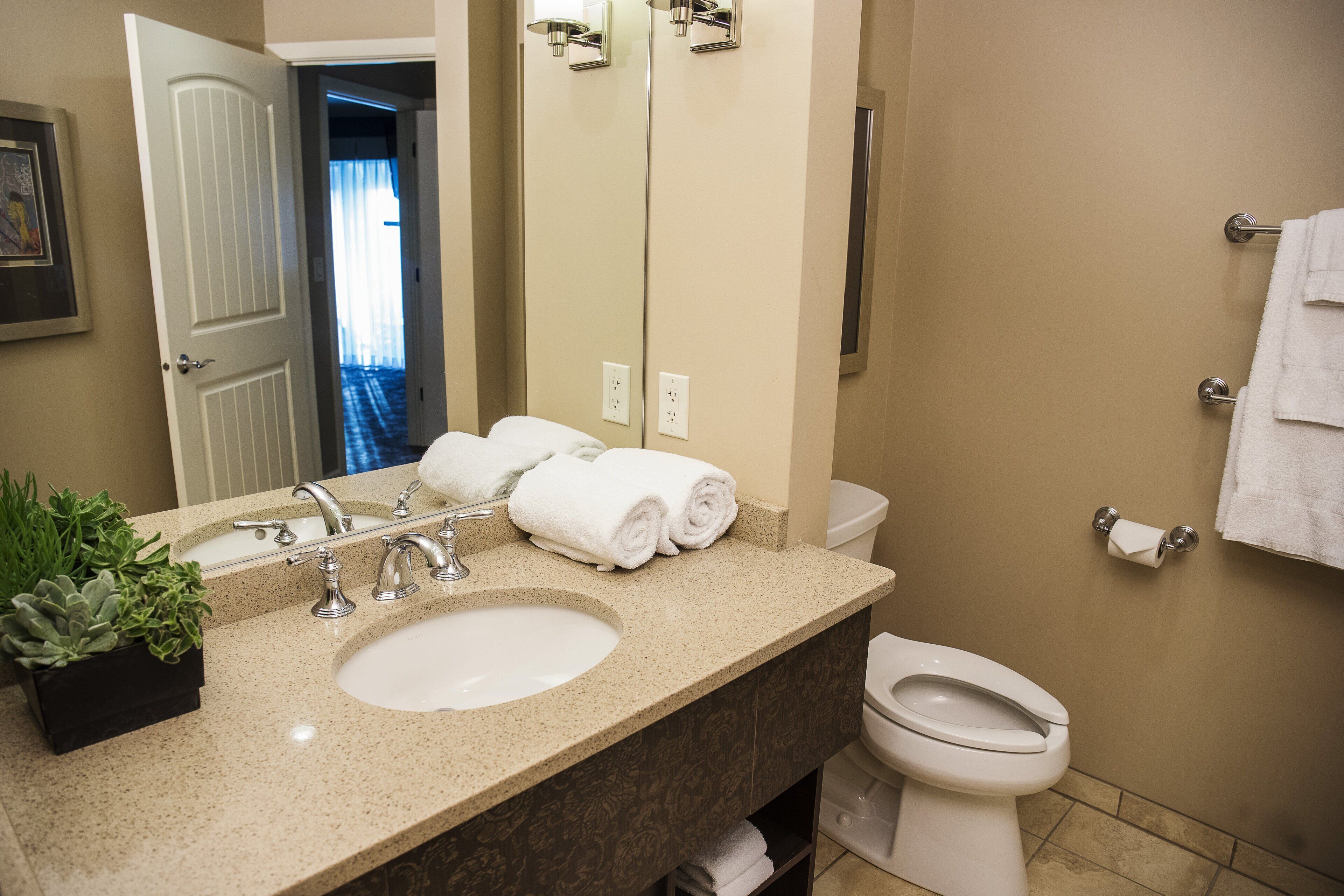 A bathroom with a sink, mirror, toilet, and towel rack.
