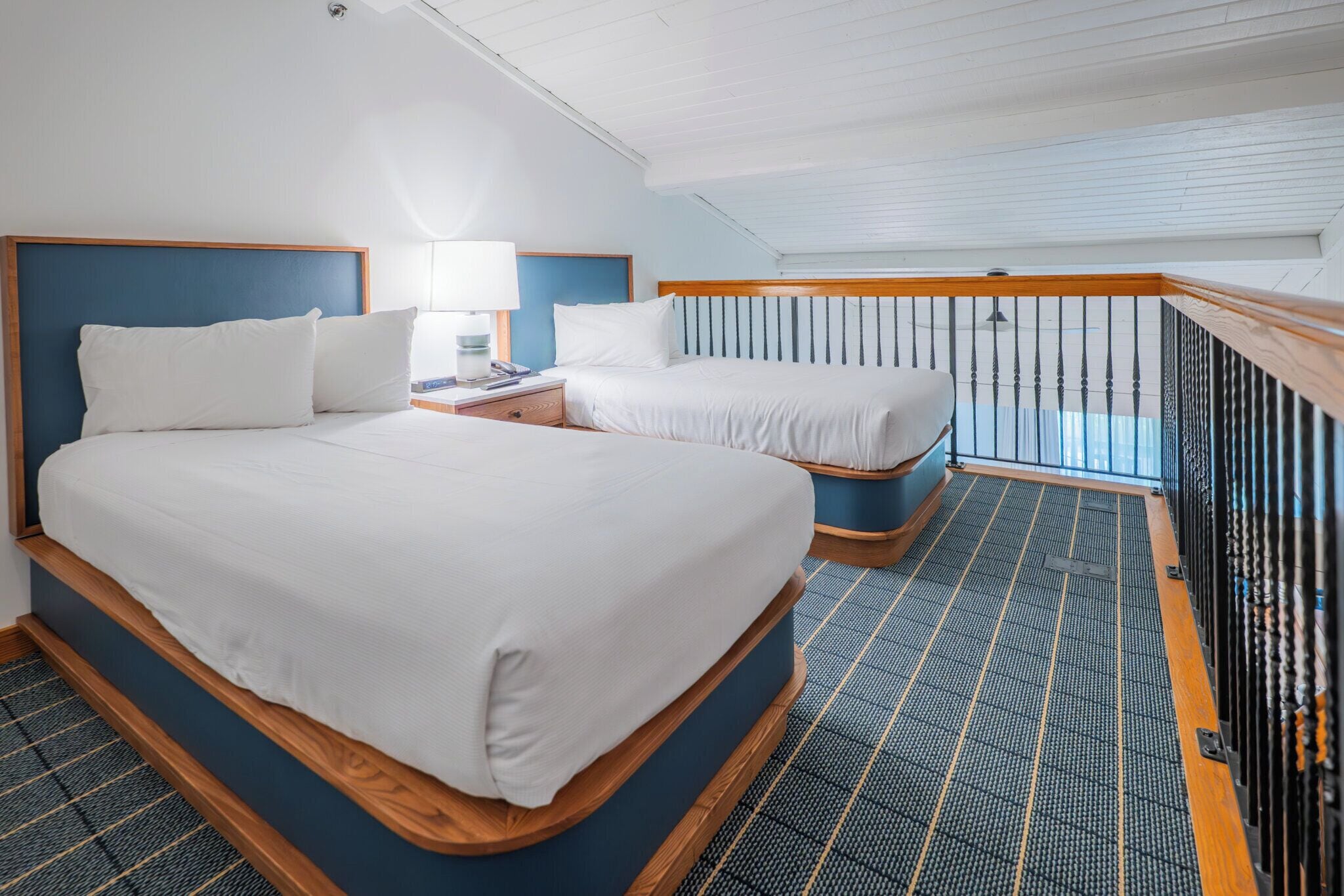 Habitación de hotel con dos camas, una mesita de noche, una lámpara y vistas al balcón.