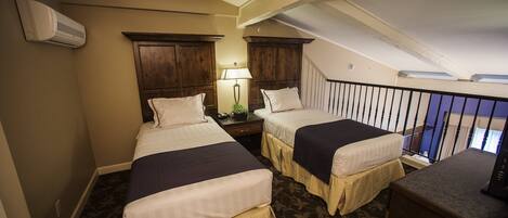 Une chambre d’hôtel avec deux lits, un bureau, une lampe et un escalier.