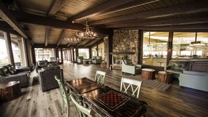 A spacious living area with a wooden ceiling, stone walls, and a fireplace. There are multiple seating areas with sofas and chairs. - Lake Lawn Resort (Delavan)