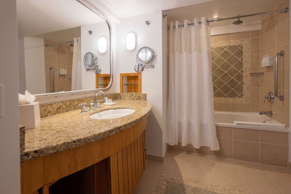 Un baño con lavamanos de granito, dos espejos, ducha con puerta de cristal y bañera.