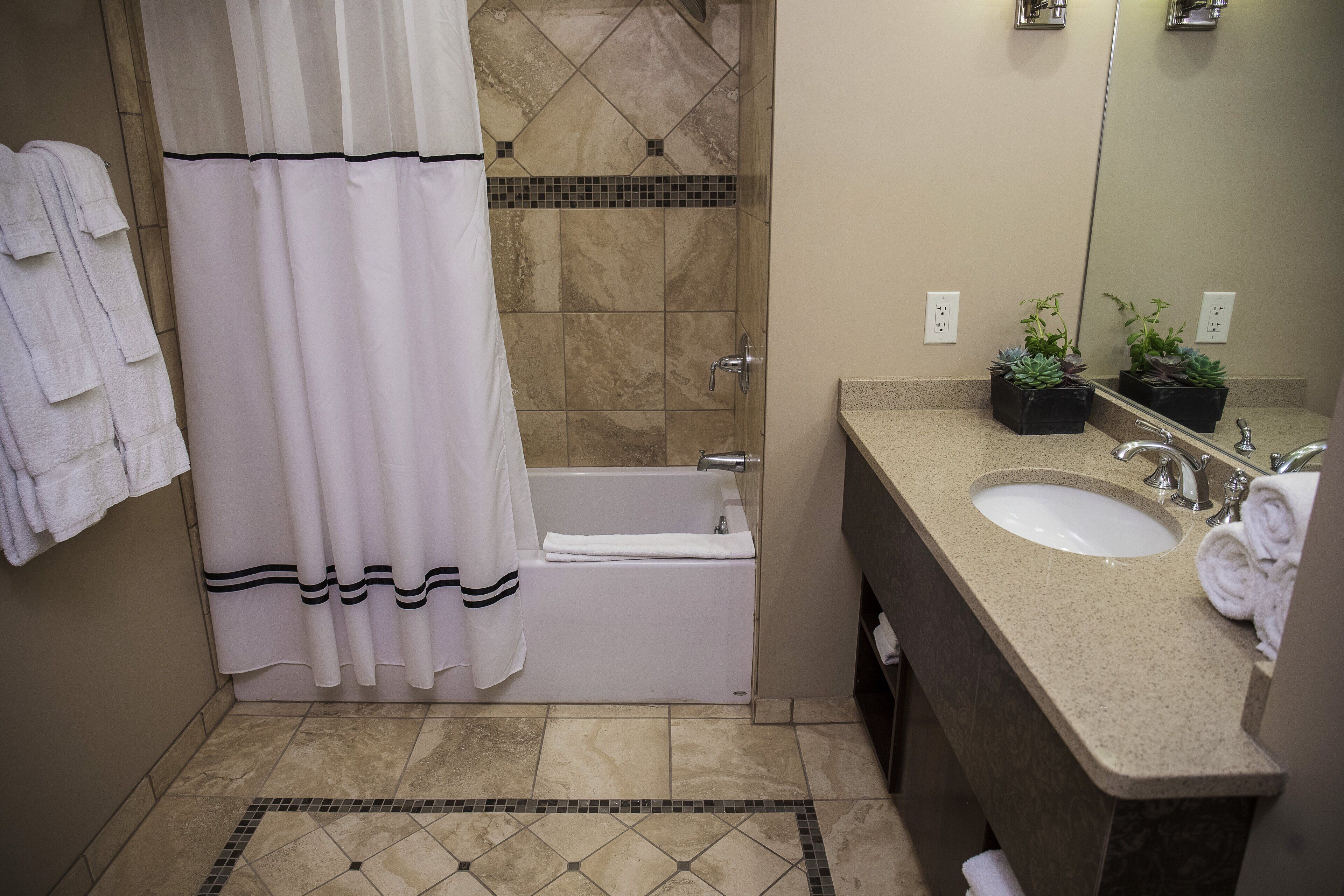 A bathroom with a bathtub, a sink, and a shower curtain.