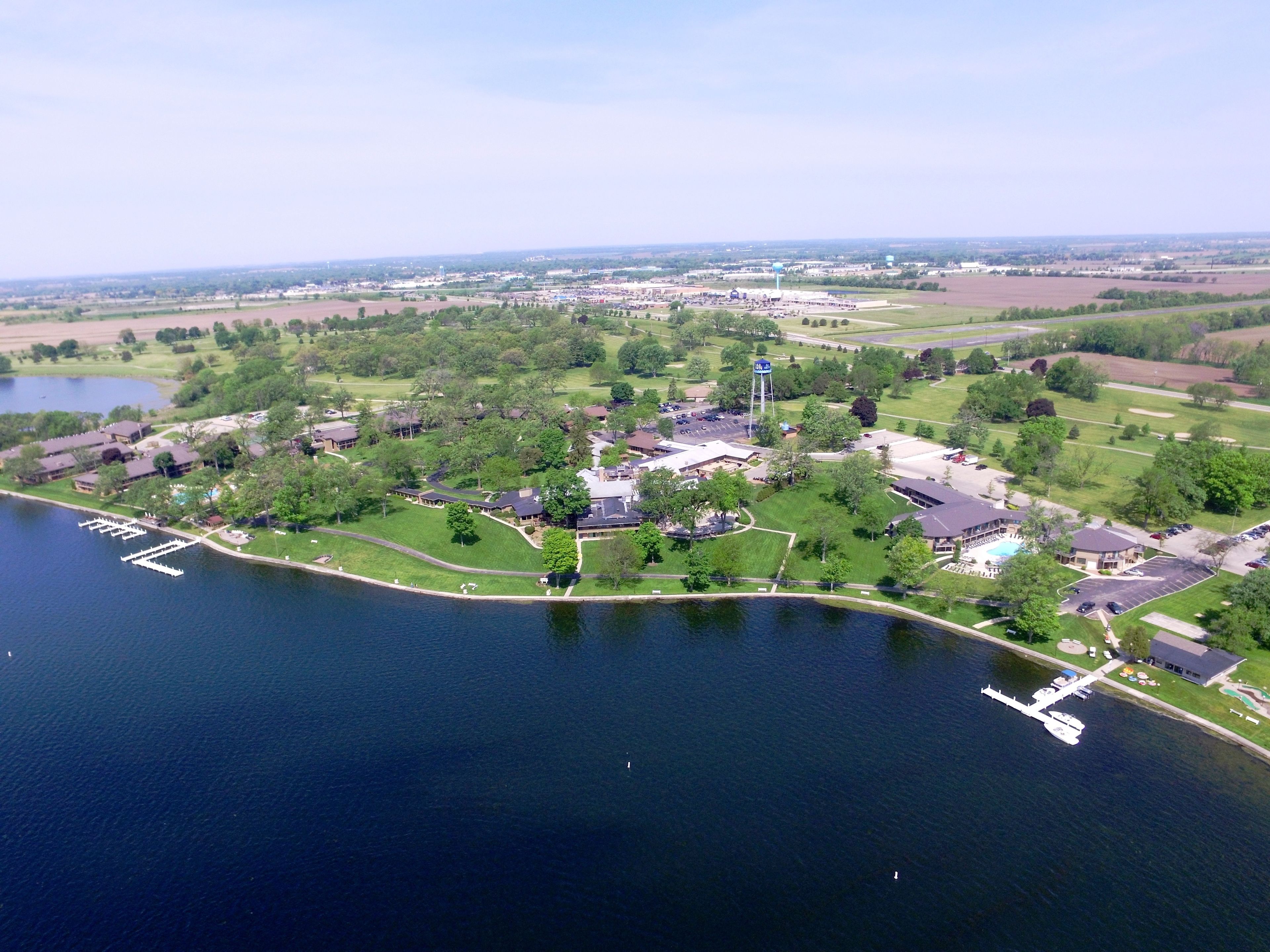 An aerial view of a lakeside community with residential buildings, a marina, and a golf course.