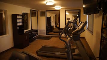 Uma academia em casa com esteiras, bicicleta ergométrica e um banco de musculação.