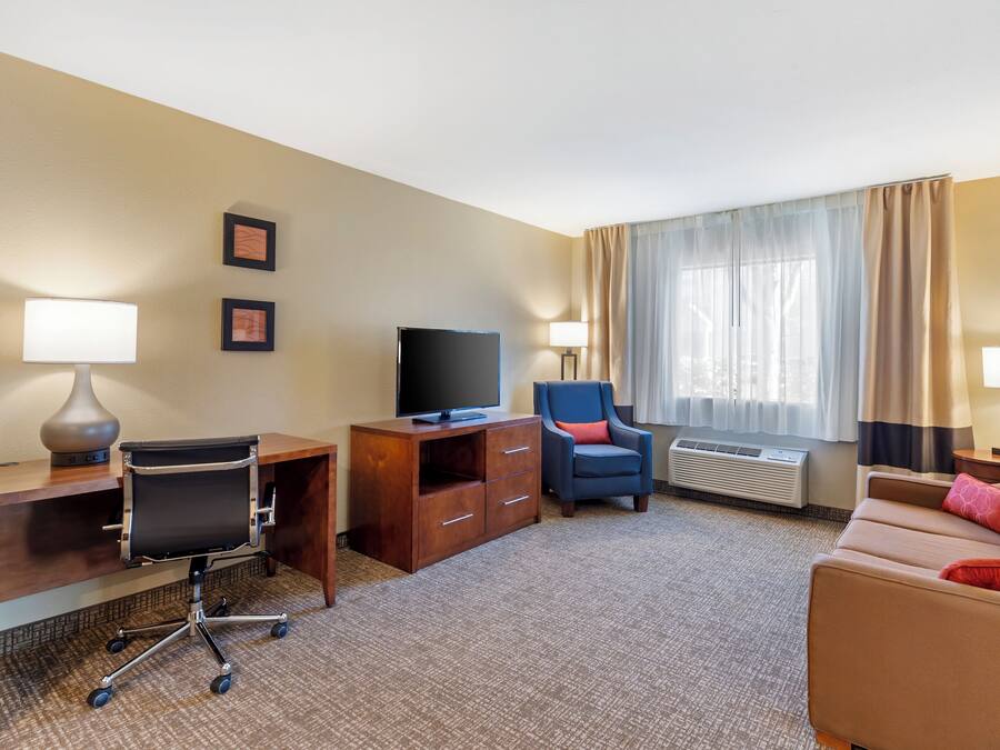 Ein Hotelzimmer mit Schreibtisch, Stuhl, Fernseher und einer Sitzecke.