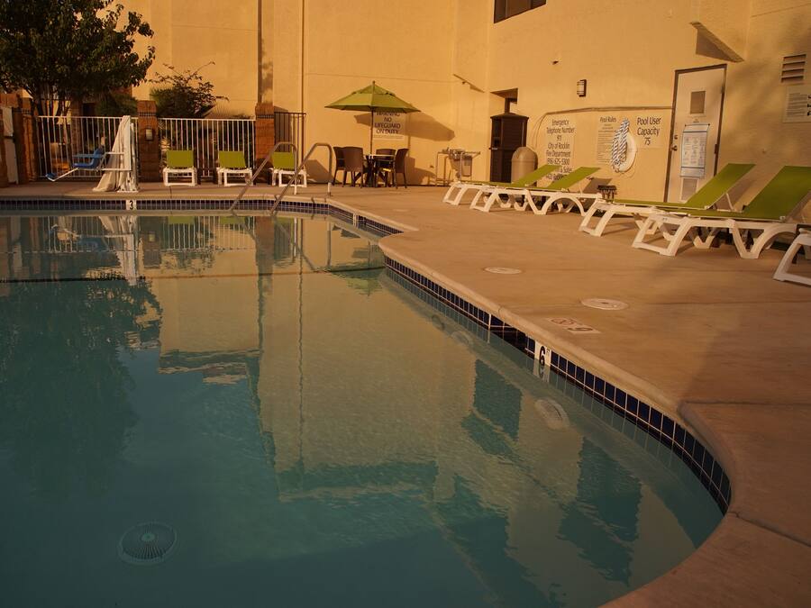 An indoor swimming pool with lounge chairs and a covered seating area.