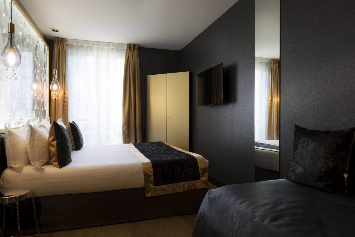 Une chambre d’hôtel moderne équipée d’un lit, d’une table de chevet et d’un téléviseur fixé au mur.