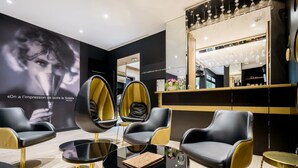 A modern interior with black and gold chairs, a round black table, and a large mirror above a bar area.