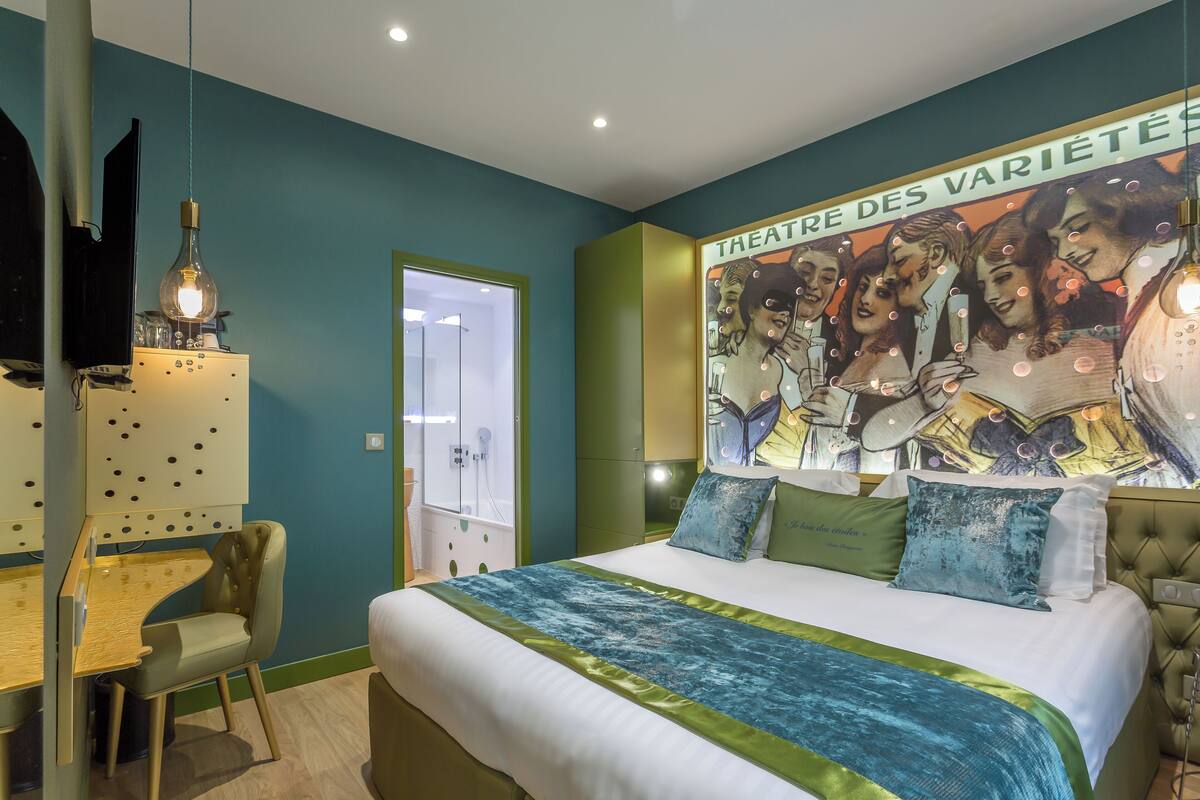 Une chambre à coucher avec un lit, un bureau et une chaise. Il y a une affiche accrochée au mur et un luminaire au-dessus du lit.