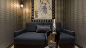 A dark blue sofa with a bottle of champagne and a glass on a table in front of it.