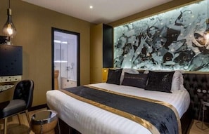 A modern hotel room with a large bed, a television, a drum, and a unique wall art piece. - Hotel Les Bulles de Paris (Paris)