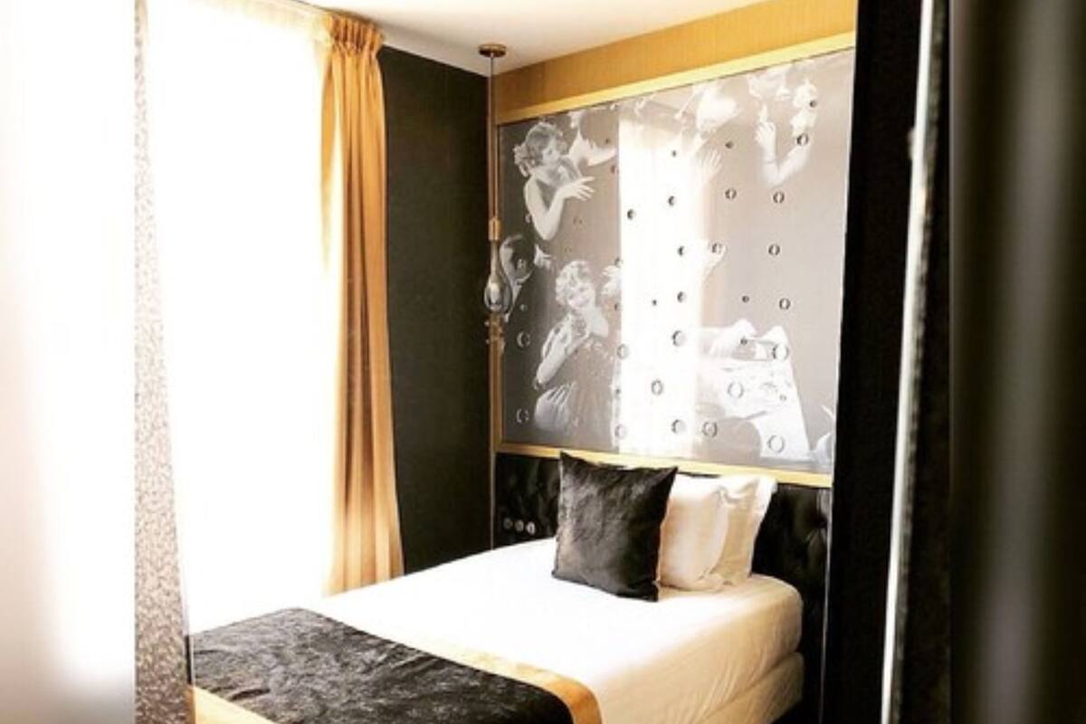 Une chambre à coucher avec un lit, une tête de lit ornée d’un motif et une fenêtre avec des rideaux.
