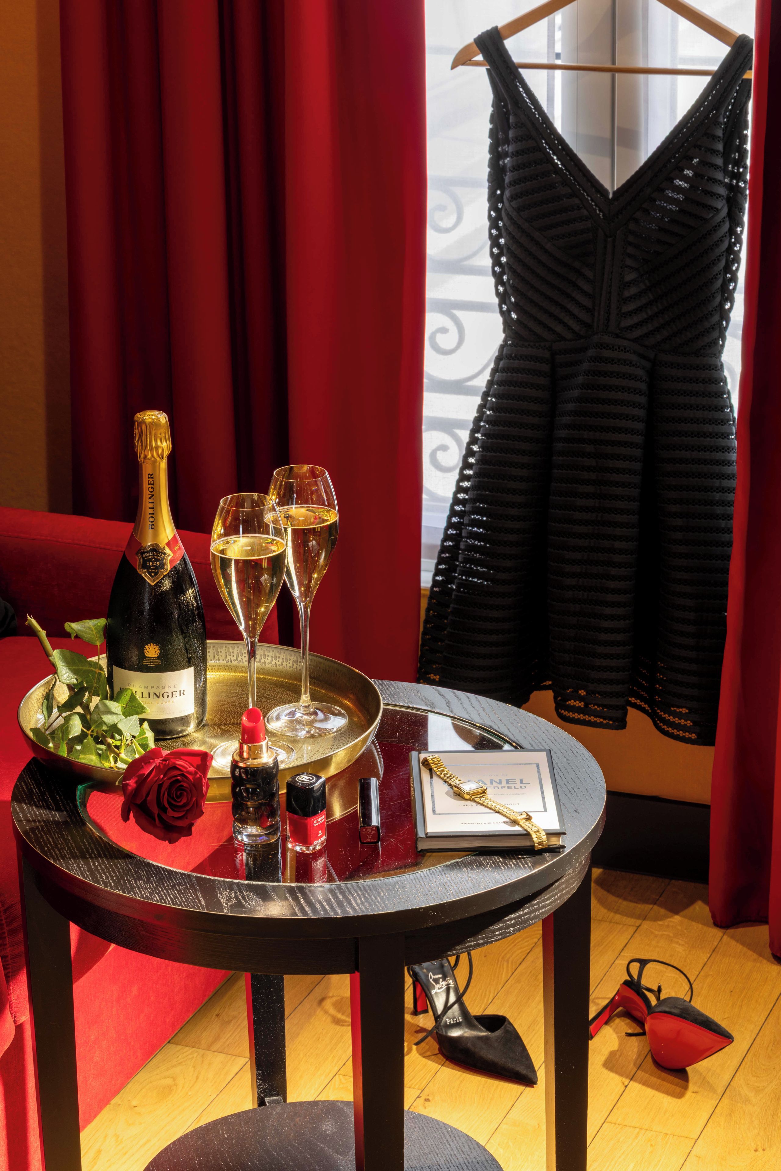 Une table avec une bouteille de champagne, deux verres, un plateau avec une rose et un livre intitulé « Chanel ».