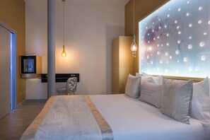 A modern hotel room with a large bed, a television, a chair, and a unique wall feature. - Hotel Les Bulles de Paris (Paris)