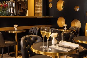 A restaurant interior with round tables, black leather chairs, and a bar area with wine glasses and bottles. - Hotel Les Bulles de Paris (Paris)
