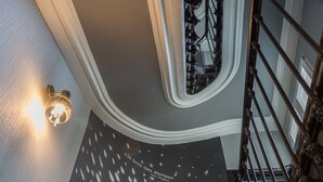 A staircase with a black and white patterned floor, a wall-mounted light, and a decorative railing.