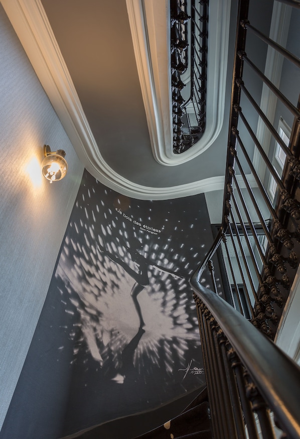 A staircase with a black and white patterned floor, a wall-mounted light, and a decorative railing. - Hotel Les Bulles de Paris (Paris)