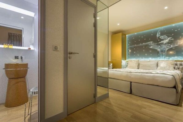 Un dormitorio moderno con un separador de vidrio, una cama y una obra de arte decorativa en la pared.