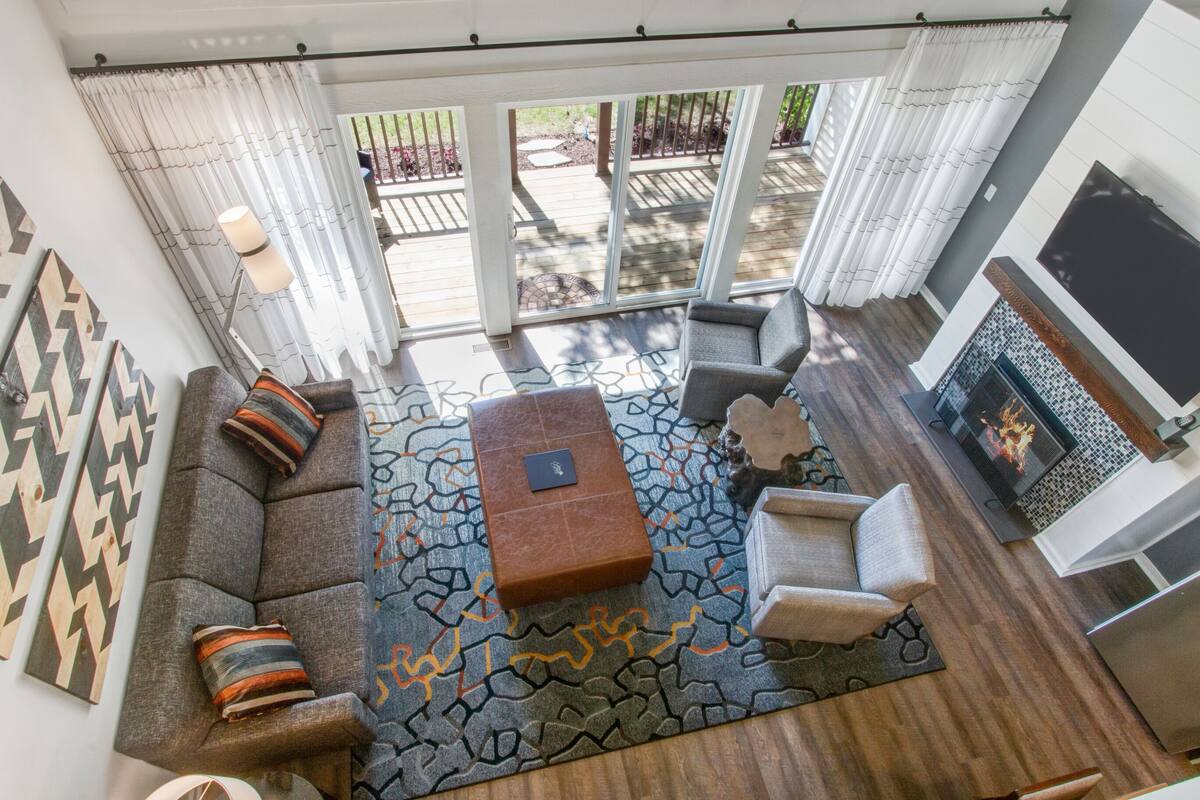 A modern living room with a gray sofa, patterned rug, and a fireplace.