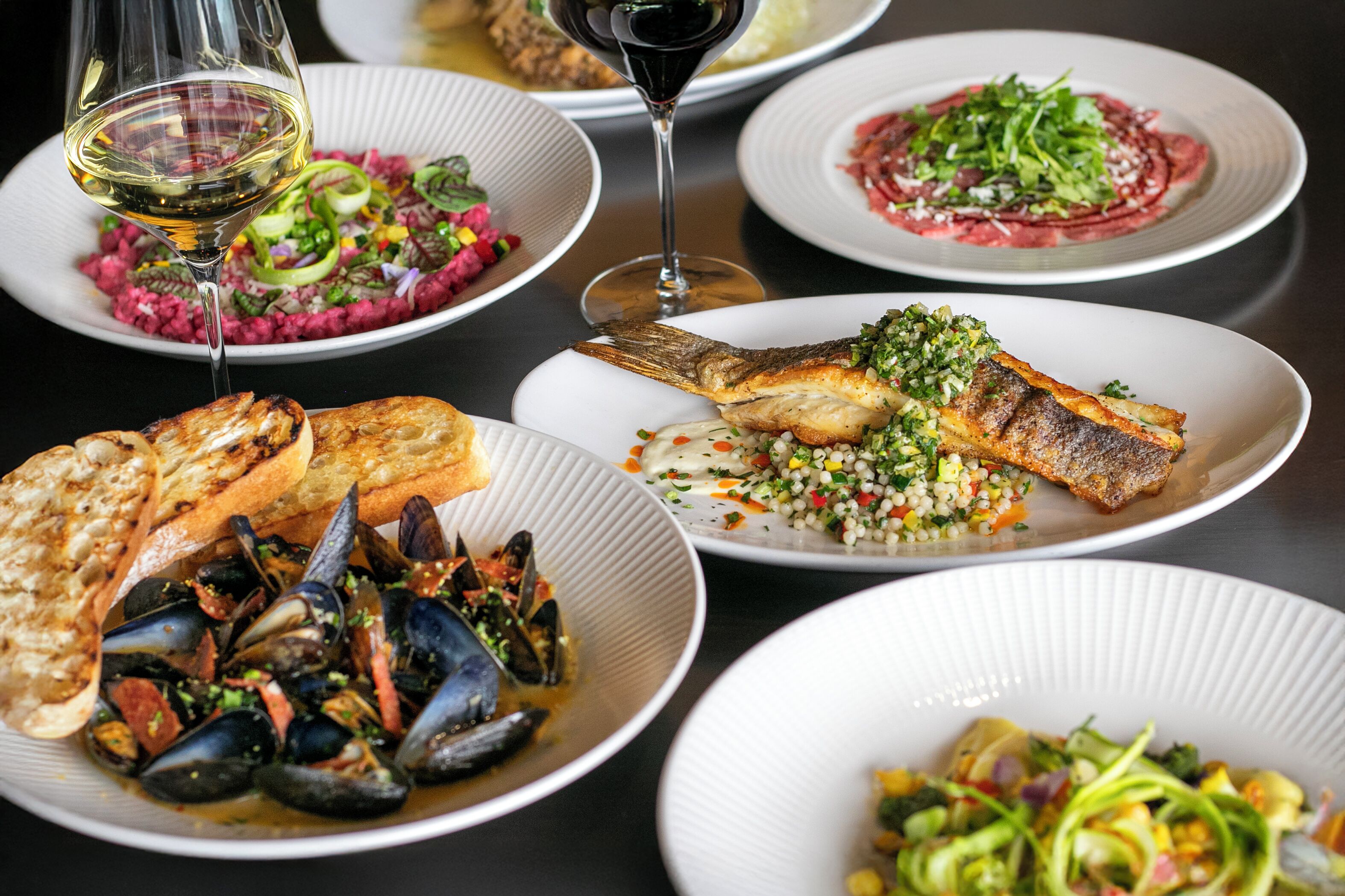 Une variété de plats présentés sur des assiettes, notamment des fruits de mer et des salades.