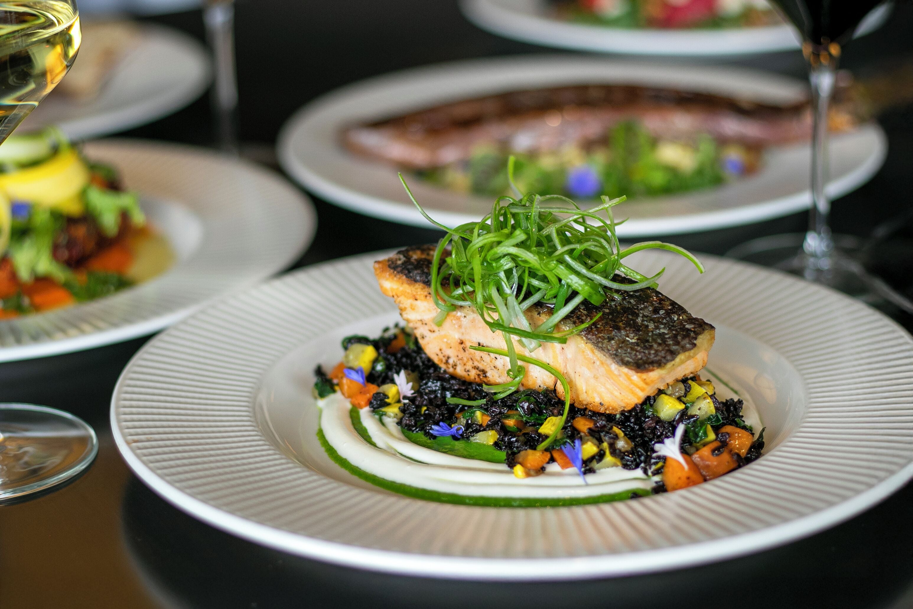 A plate of food with a piece of salmon on top of a bed of vegetables.
