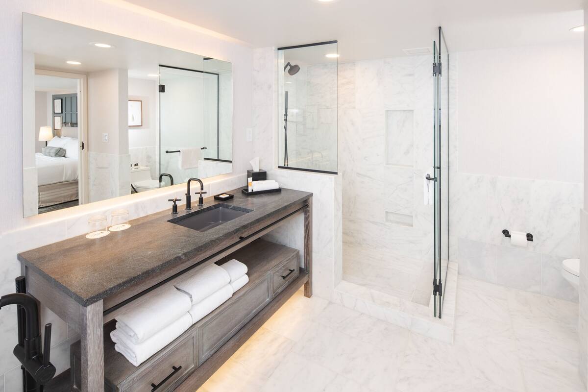 A modern bathroom with a large mirror, a sink, and a shower.