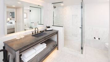 Une salle de bain moderne avec un grand miroir, un lavabo et une douche.