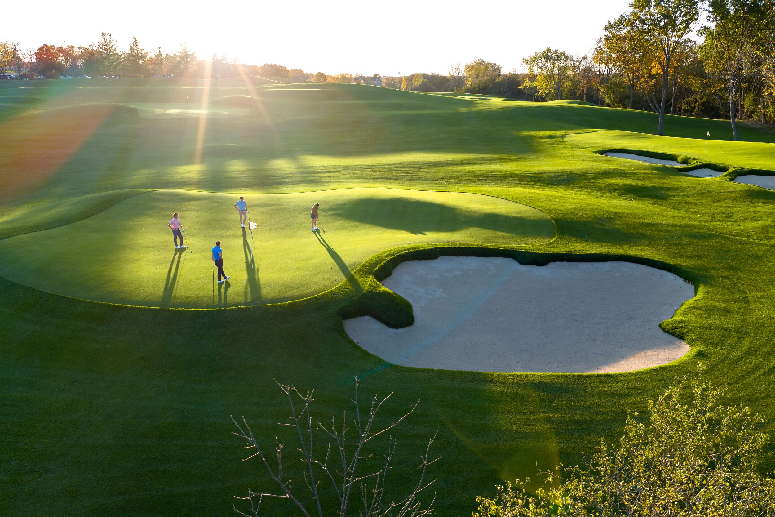 A golf course with sand bunkers, a flag, and players.