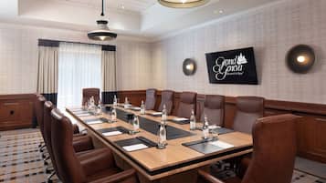 Une salle de conférence avec une longue table, des fauteuils en cuir marron et une enseigne « Grand Geneva Resort & Spa » accrochée au mur.