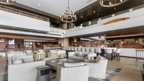 Eine großzügige Lobby mit mehreren Sitzbereichen, einer Bar und einer hohen Decke mit moderner Beleuchtung.