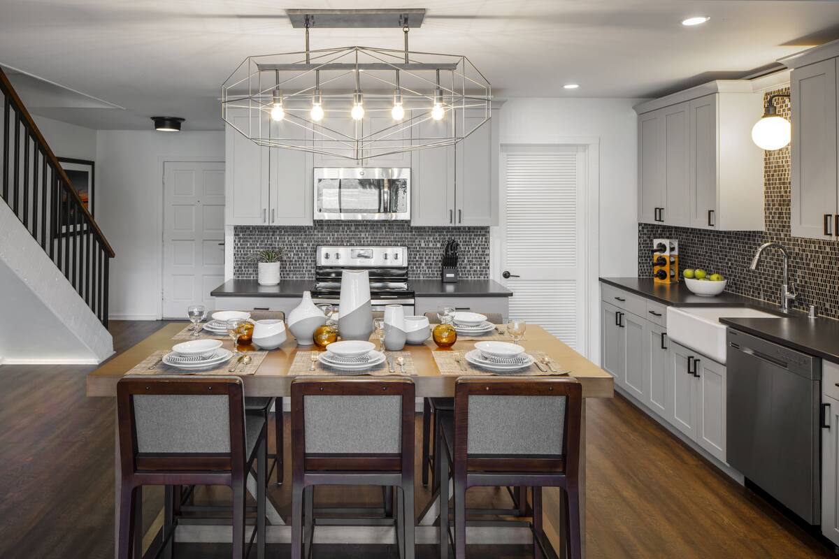A modern kitchen with a central island, white cabinetry, and a stainless steel range hood.