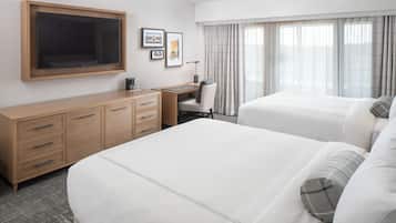 Una habitación de hotel con una cama grande, un escritorio, una silla, un televisor y un armario.