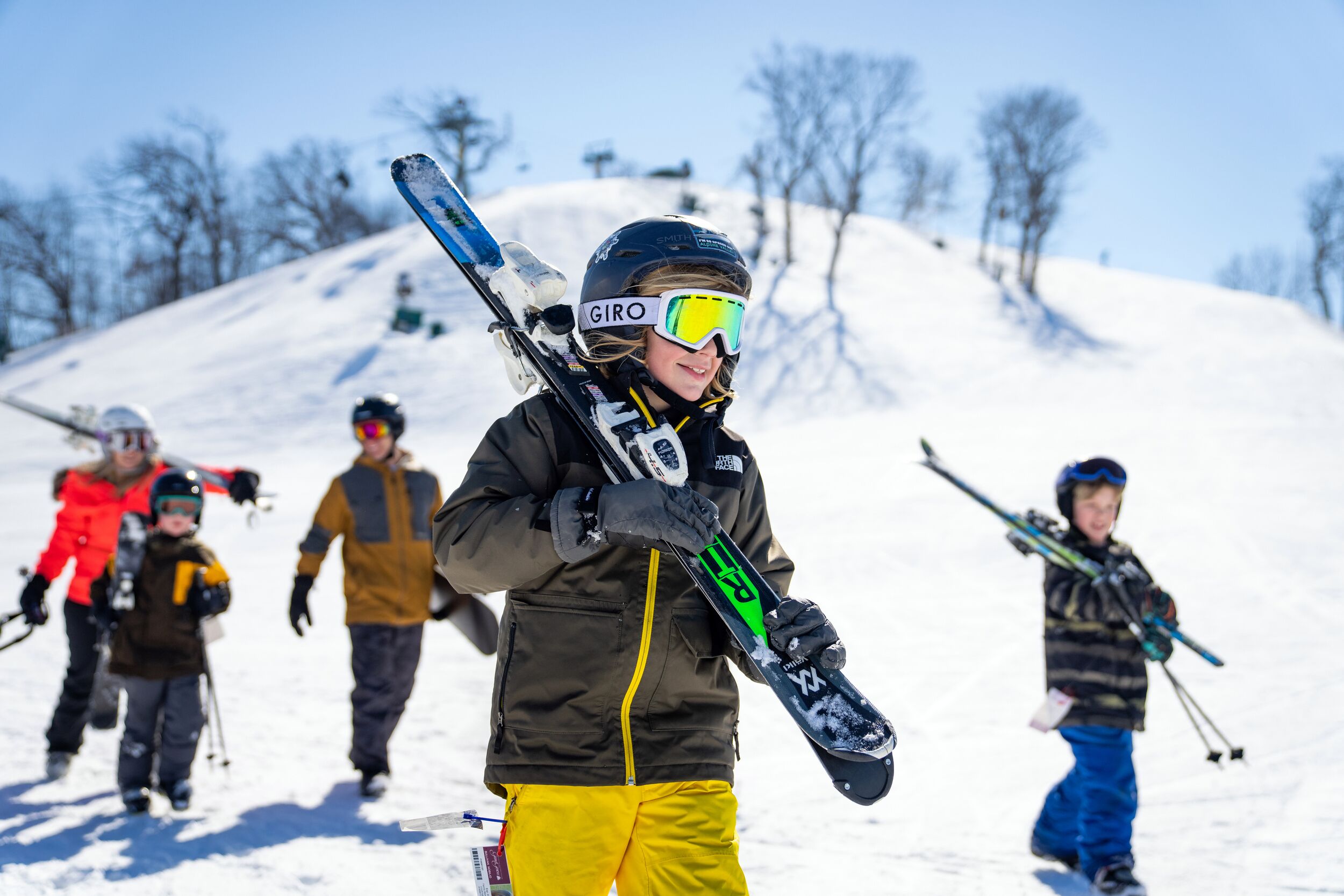 A group of people on a snowy slope, some holding skis.