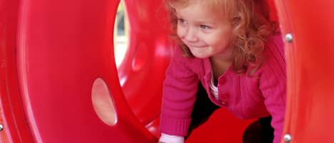 A child in a red slide tunnel.