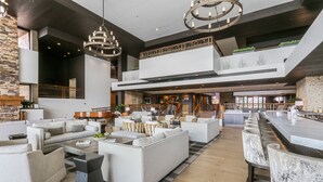 Ein großzügiger, mehrstöckiger Wohnbereich mit moderner Einrichtung, einer zentralen Sitzecke und einer Bar/Lounge mit hohen Hockstühlen.
