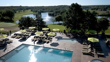 Una piscina techada, una piscina al aire libre, sombrillas