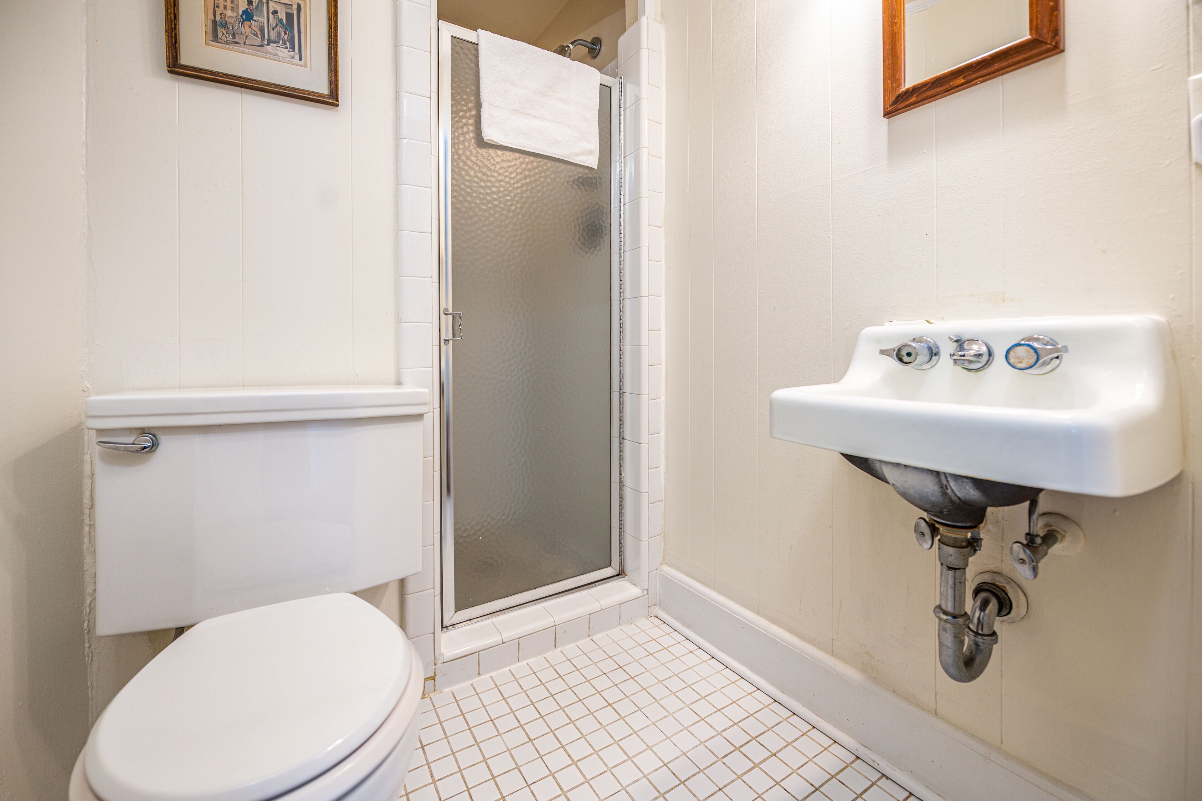 Een badkamer met toilet, douche met glazen deur en wastafel.